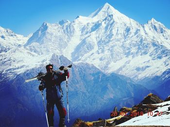 Man standing on snowcapped mountain against sky