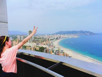 Woman standing by sea against sky