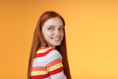 Young woman looking away against yellow background