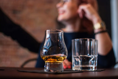 Close-up of scotch whiskey in glass with people in background at bar