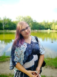 Portrait of young woman standing by lake