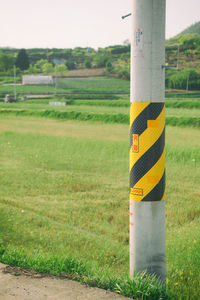 Wooden post on field by road
