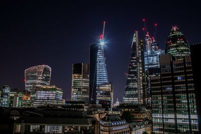 Illuminated buildings in city against sky at night