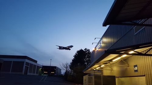 Low angle view of airplane flying against clear sky at night