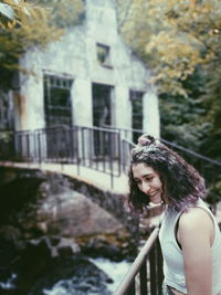 Smiling young woman looking down while standing on footbridge