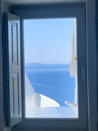 Scenic view of sea against clear blue sky seen through window