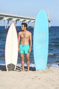 Full length of shirtless man standing on beach