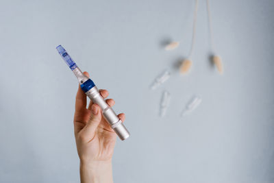 Cropped hand holding syringe against white background