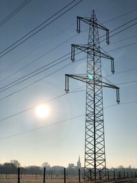 Low angle view of electricity pylon against sky during sunset