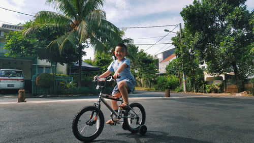 Woman riding bicycle on road against trees