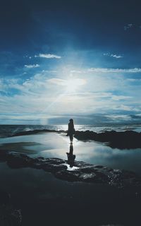 Silhouette woman standing on shore at beach against sky