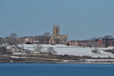 Sea by buildings against clear sky