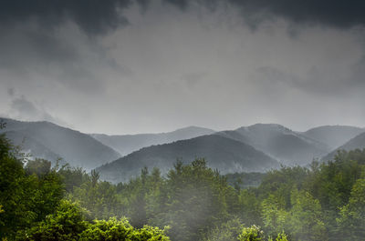 Scenic view of foggy mountains against sky