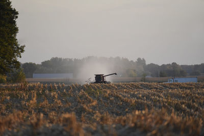 Scenic view of farmer working in an agricultural field against sky