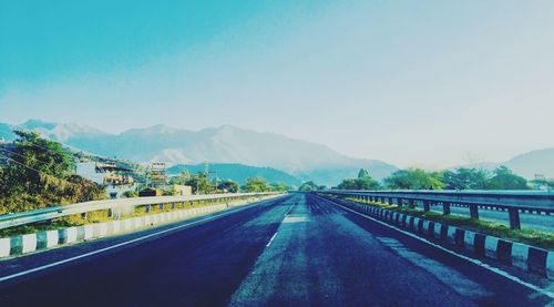 Empty road against mountains and clear sky