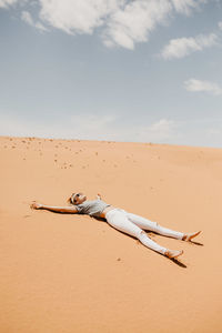 Woman lying down on desert in sunny day