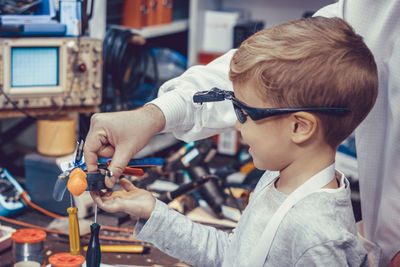 Little boy testing magnetic field during physics school science project in engineering lab.