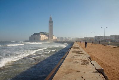 Low angle view of hassan ii mosque by sea against sky
