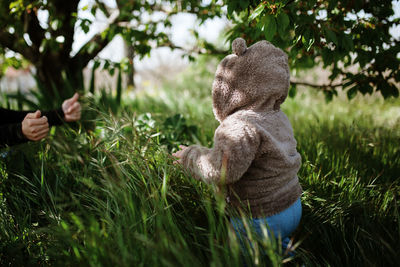 Baby girl wearing warm clothing while walking amidst grass