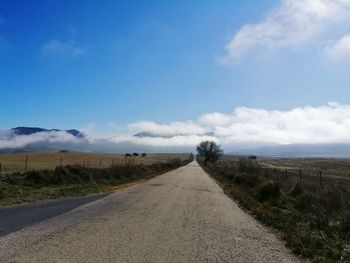 Road leading towards landscape against sky