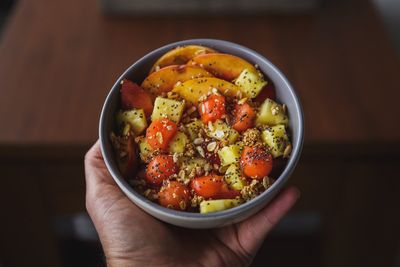 High angle view of hand holding salad in bowl on table