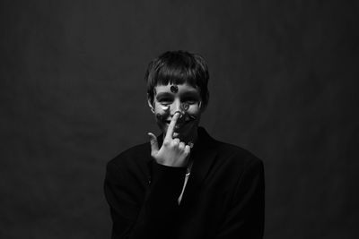 Young man standing against black background