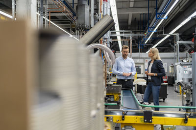 Female manager standing with male coworker at production line