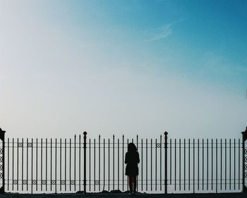 Woman standing by railing against sky