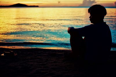 Silhouette man looking at sea during sunset