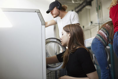 Young male and female friends doing laundry at laundromat