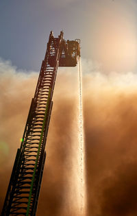 Low angle view of hydraulic platform spraying water against sky