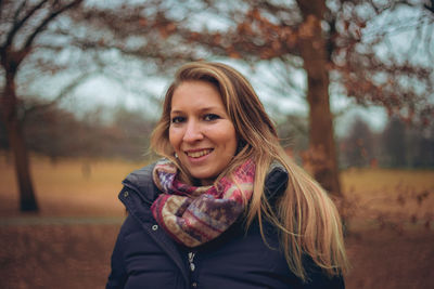 Portrait of smiling young woman standing outdoors during autumn