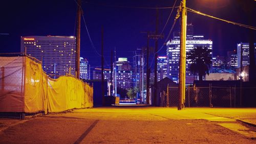 Illuminated street amidst buildings in city at night