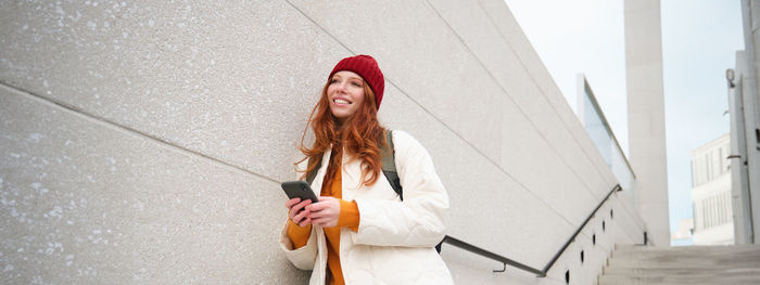 Low angle view of woman standing against wall