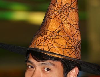 Cropped portrait of man wearing witch hat with spider web pattern