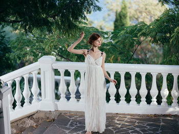 Woman standing by railing against trees