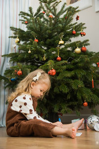 Little toddler girl sit on floor and write or draw letter for santa. 