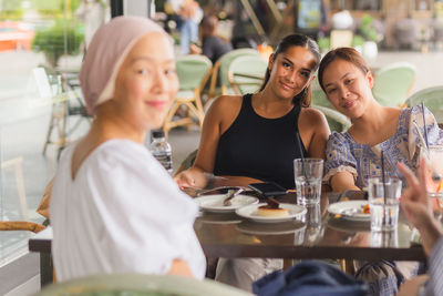 Portrait of smiling friends sitting at restaurant