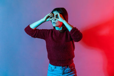 Midsection of young woman standing against red background