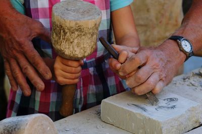 Midsection of man teaching carving to person 