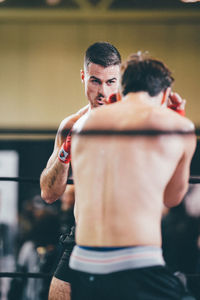 Rear view of shirtless man sitting at home