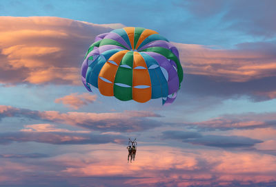 Low angle view couple flying against sky during sunset