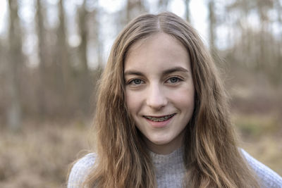 Close-up portrait of smiling teenage girl in forest