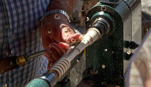 Midsection of man holding power tool while standing in workshop