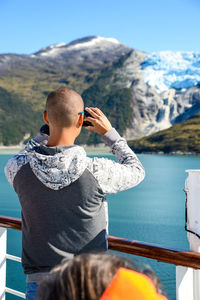 Rear view of man using mobile phone against mountain