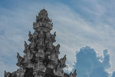 Low angle view of carved built structure against cloudy sky