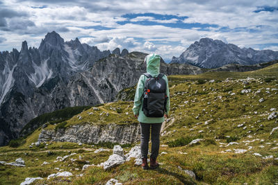 Rear view of man standing on mountain against sky