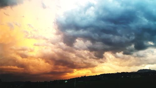 Silhouette landscape against dramatic sky during sunset