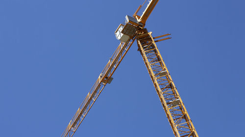 Low angle view of crane against clear blue sky