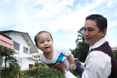 Cheerful father and son against sky